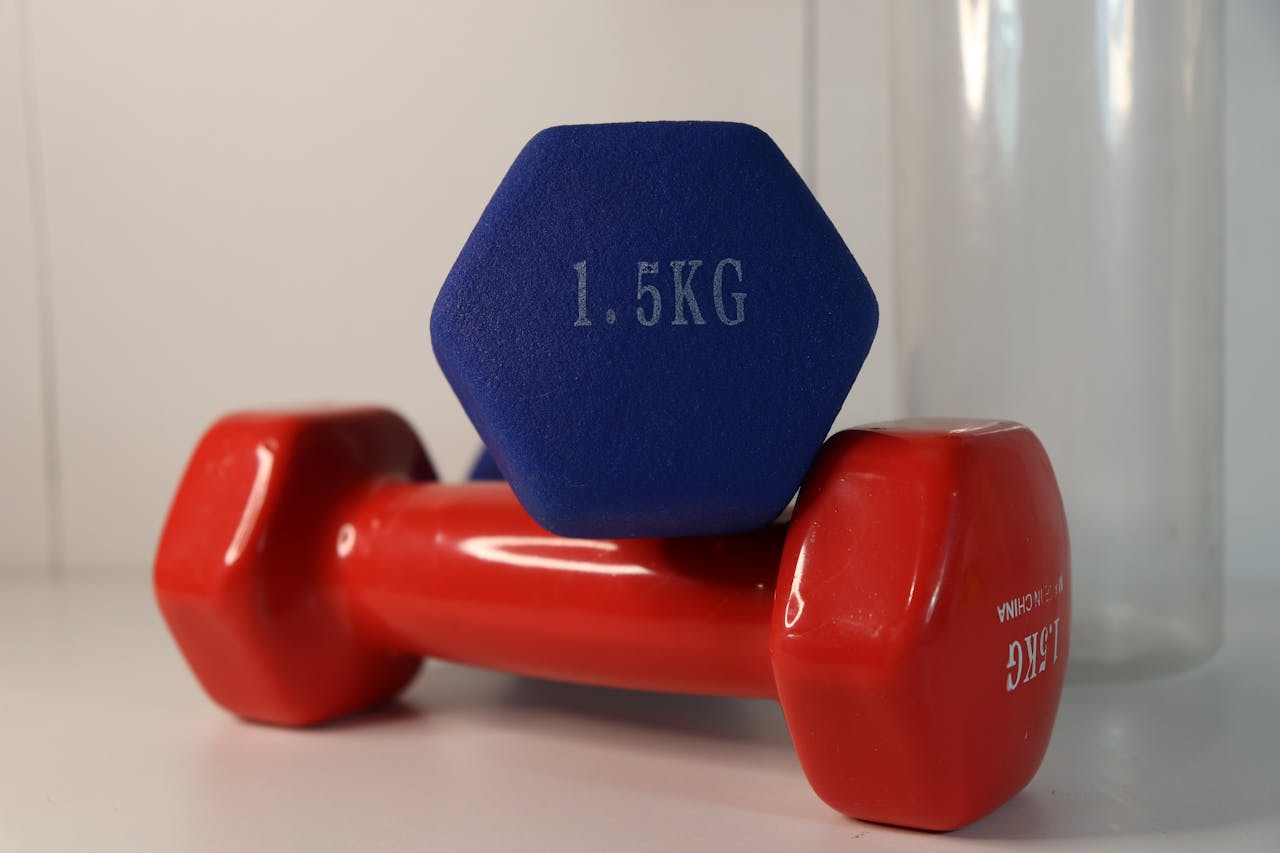 Two vibrant dumbbells positioned on a white surface with fitness emphasis.