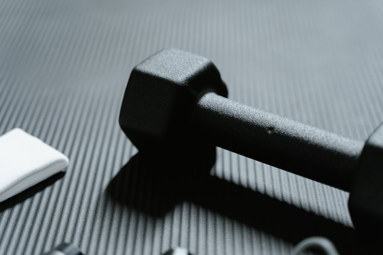 Services-02 Detailed view of a black dumbbell on textured mat for fitness workout