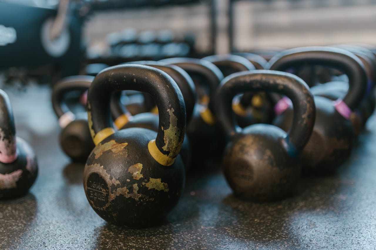A collection of black kettlebells on a textured gym floor, perfect for fitness enthusiasts.